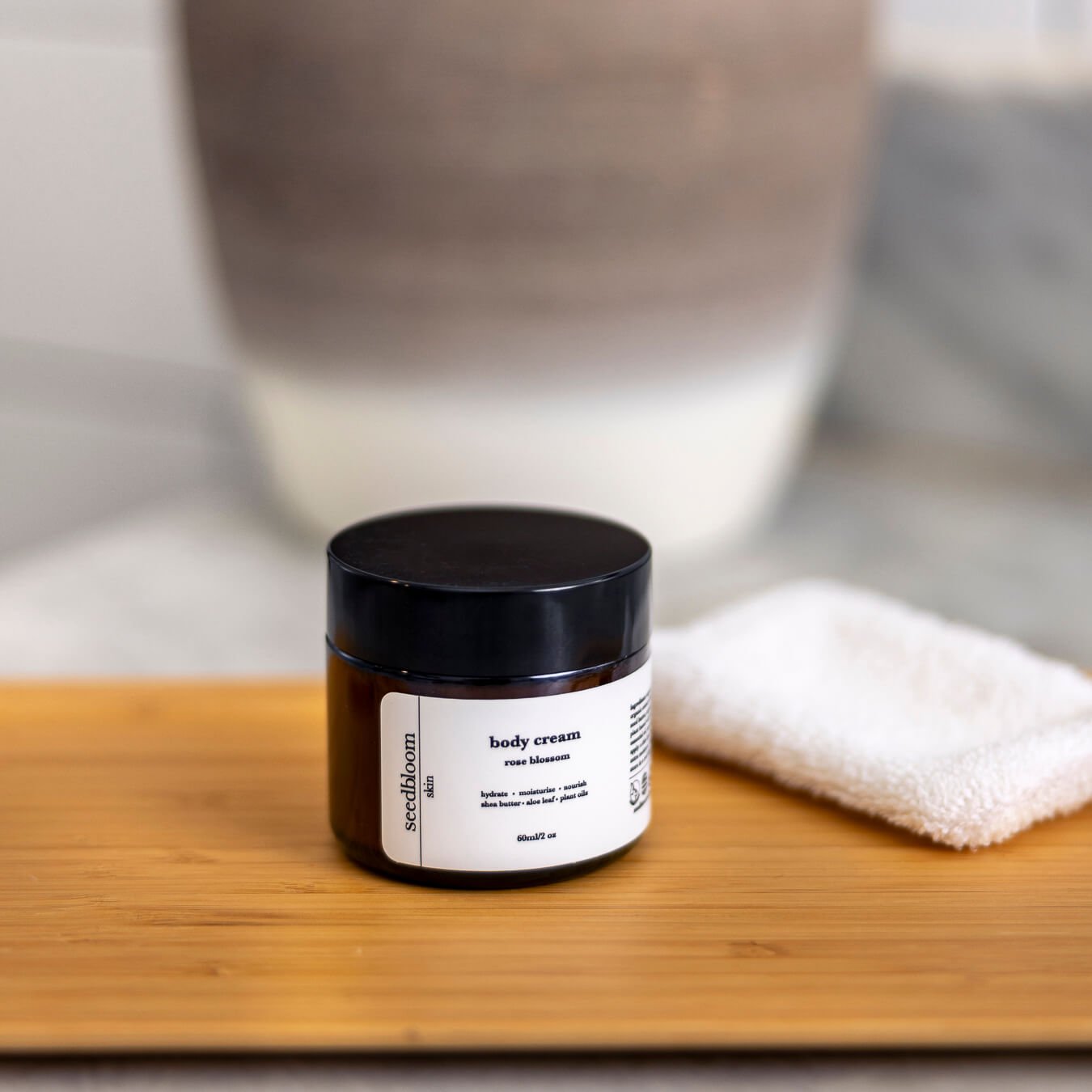Floral Body Lotion on a bamboo tray in front of a clay vessel