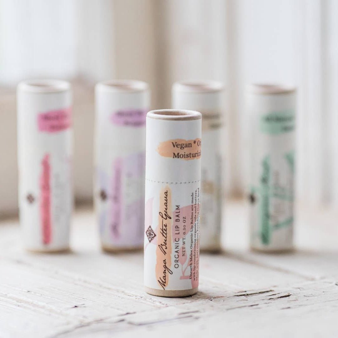 mango butter lip balm in front of other flavors on a sunny window ledge