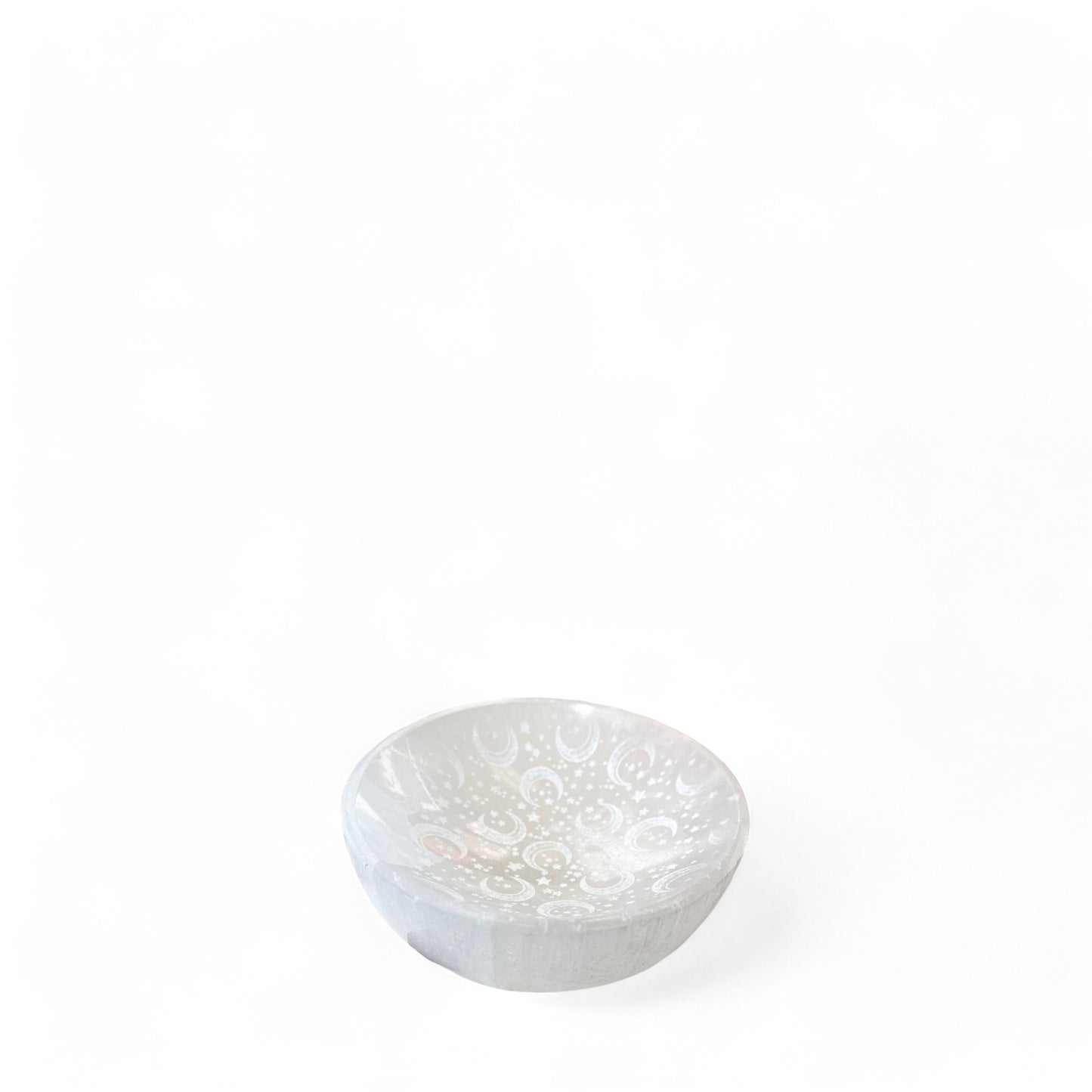 A small selenite crystal bowl with moon and stars etching