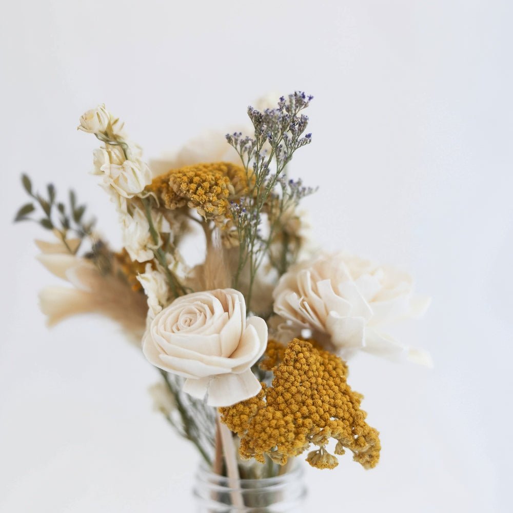 Wood flower diffuser with sola blooms and dried florals in a clear glass vessel