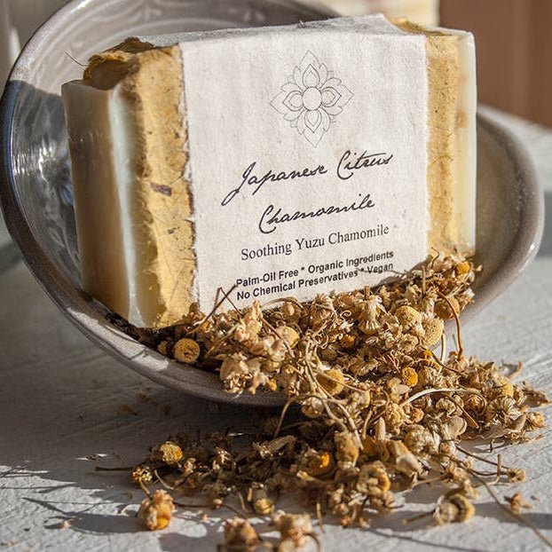 Bar of Japanese Citrus Chamomile soap with a label on a dish with dried flowers