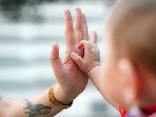 Hand of a women with a baby: Self-Care Gifts for New Moms help them recharge