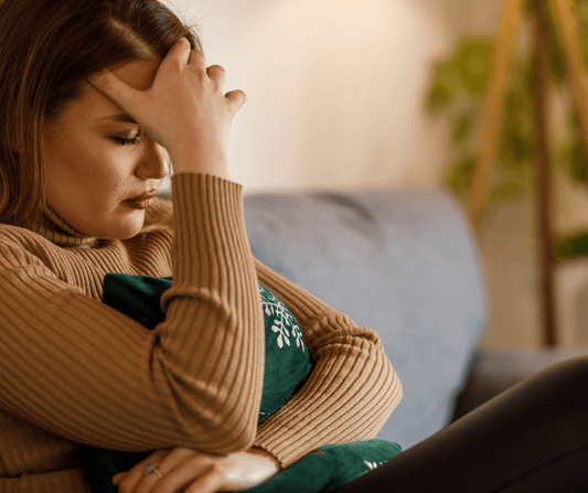 Woman on couch with hand on her forehead