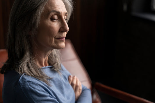 Woman sitting on couch with her arms folded looking pensive and tired