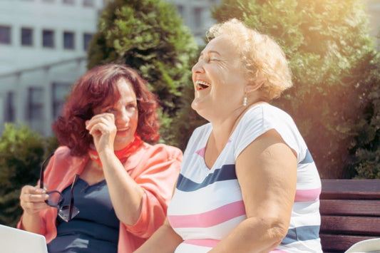 Two women sitting on a bench having a good laugh