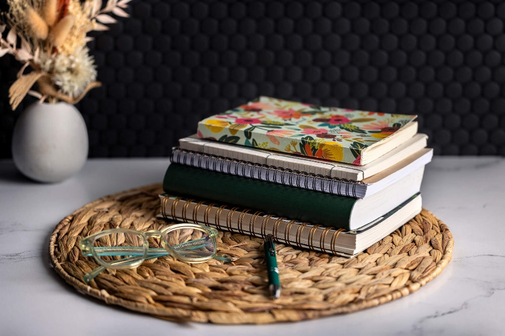 eco-friendly spiral journals and notebook on counter with dried flowers and glasses