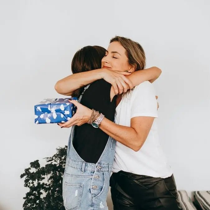 Two women hugging each other to show appreciation with a Thank You gift 