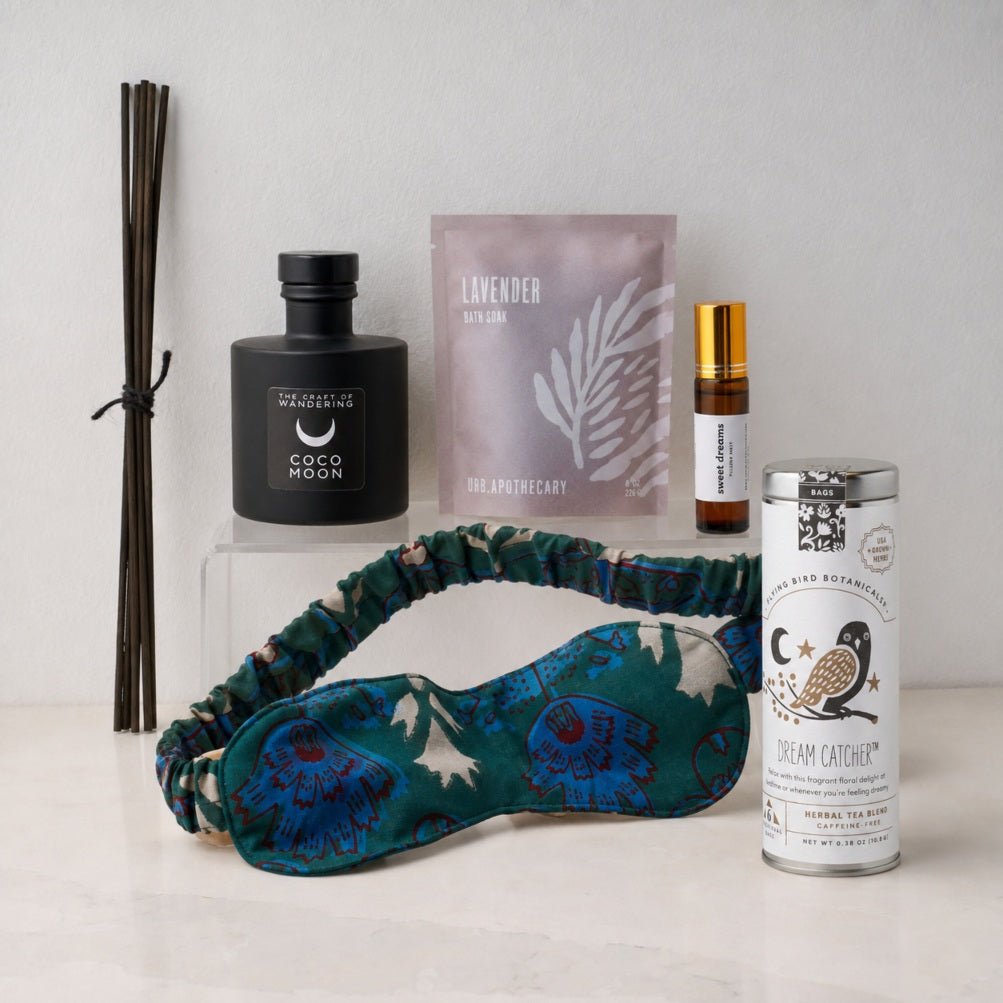 Items from the Dreamland box including bath salts, eye mask, aromatherapy, and tea on a white marble counter. 