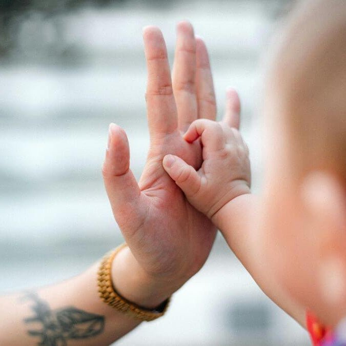 A new mom holding her hand up to her baby