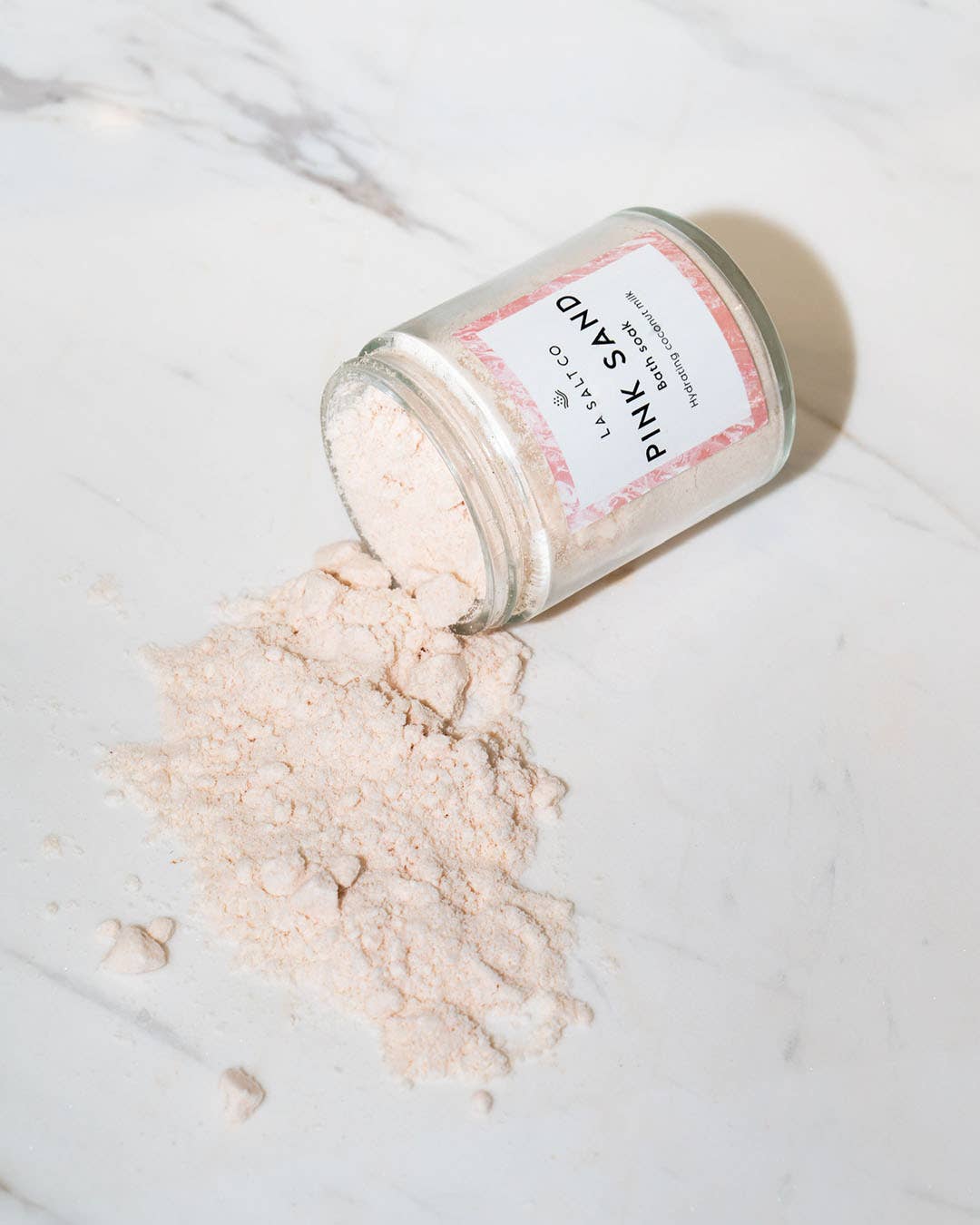 Jar of pink sand coconut milk bath soak
with a label on a marble surface