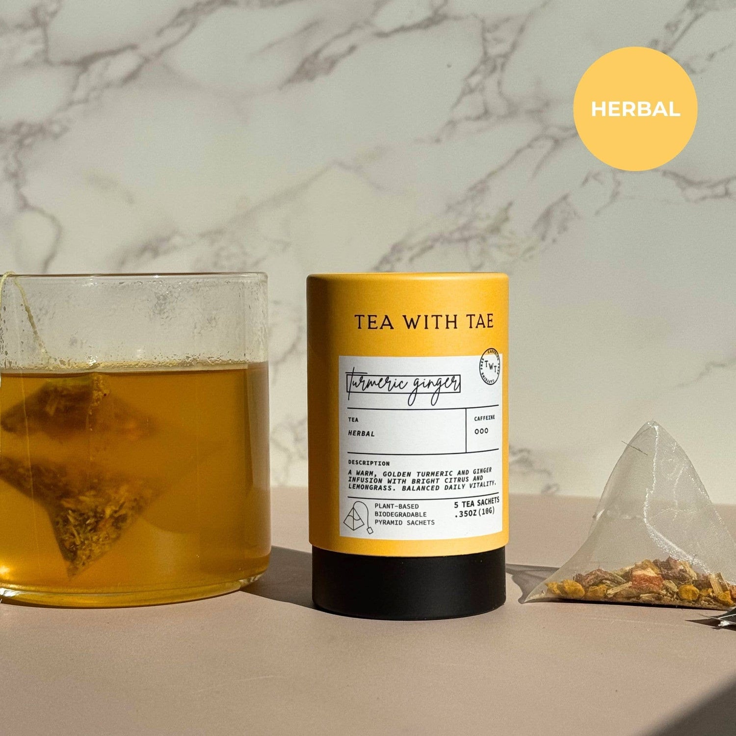 Turmeric Ginger Tea packaging with a glass of tea and tea bag on a marble surface