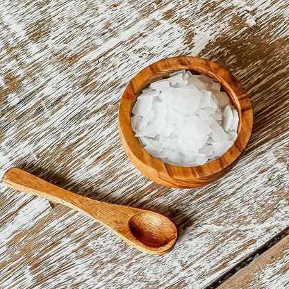 Wooden bowl with bath flakes on a rough wood table. 