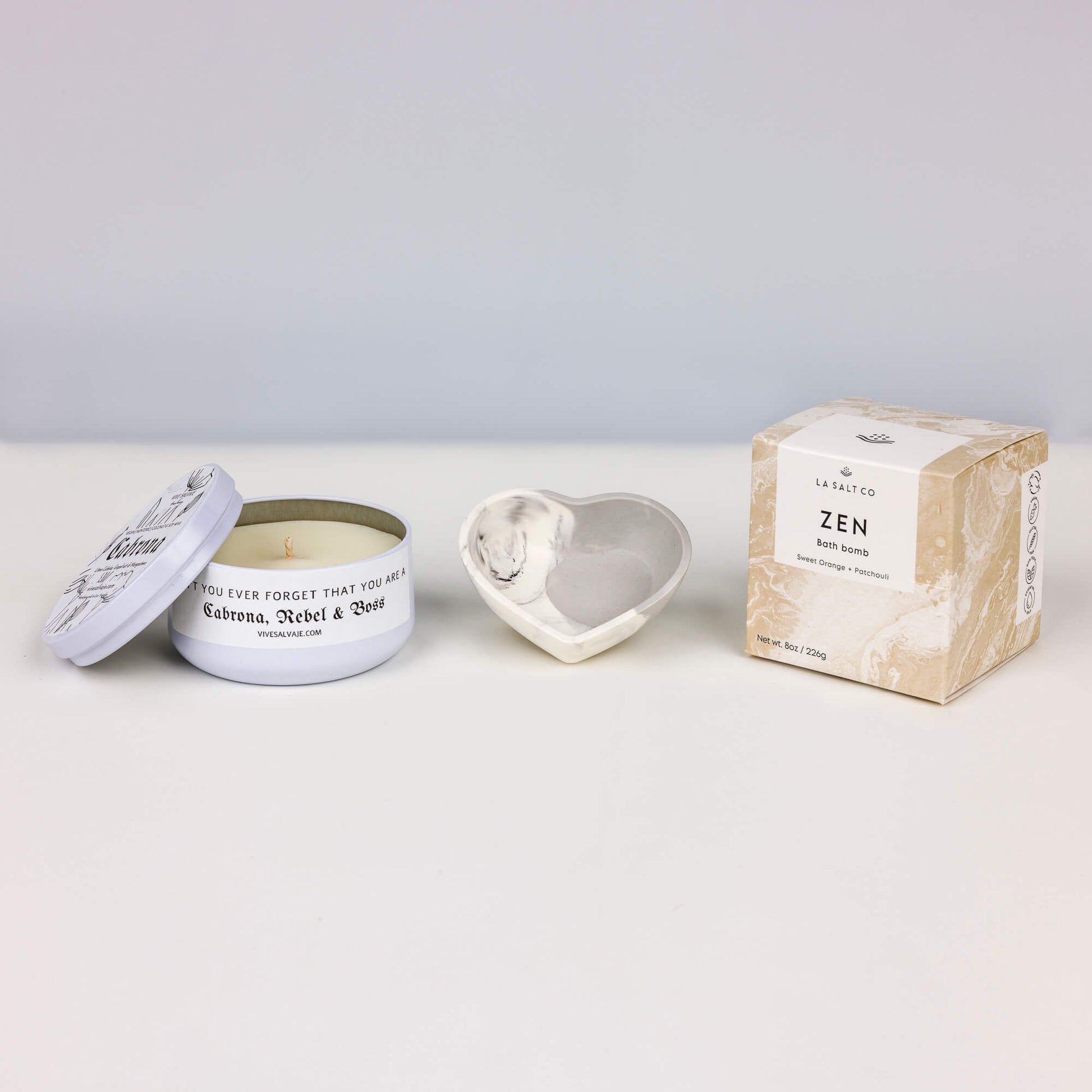 The contents of the Boss Box, including the Cabrona candle, Zen bath bomb, and heart shaped tray on a white background. 