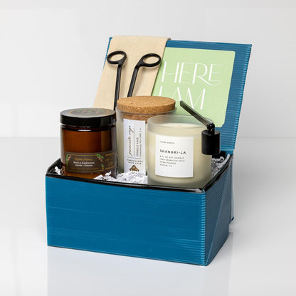 Blue gift box containing a Candle Care Tool Set, Myrrh + Frankincense candle, Pomelo Sage Candle, and Shangri-La Frosted Candle.