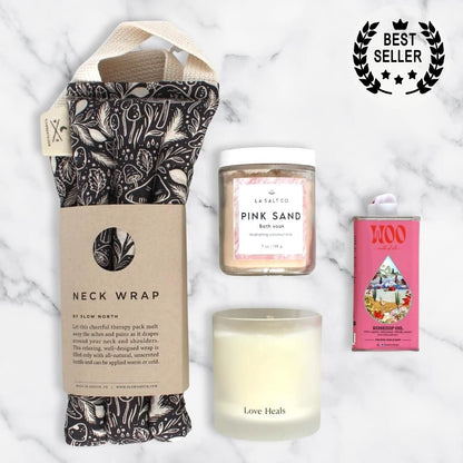 Overhead photo of the contents of the Melt Gift Box for rest and relaxation including weighted neck wrap, candle, oil, and Pink Sand bath soak