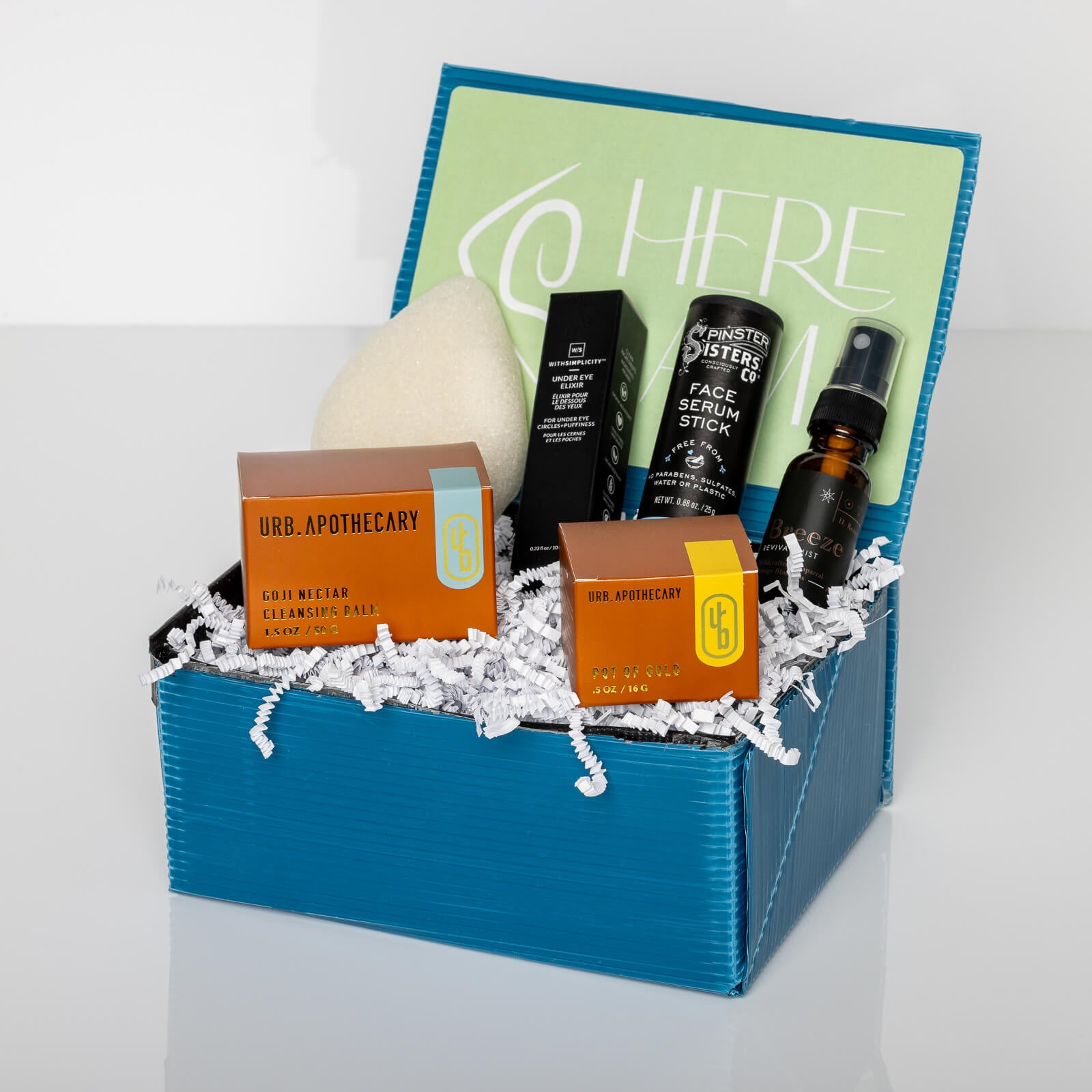 Blue gift box containing Pot of Gold Regenerative Face Balm, Breeze Toner, Konjac sponge, Goji Nectar Cleanser, Face Serum stick, and Eye Elixir