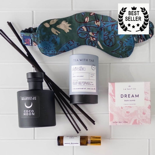 Items from the Sweet Sleep Natural Sleep kit including bath bomb, eye mask, aromatherapy, and tea on a marble counter.