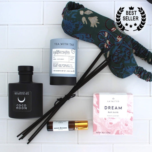 Items from the Sweet Sleep Natural Sleep kit including bath bomb, eye mask, aromatherapy, and tea on a marble counter.