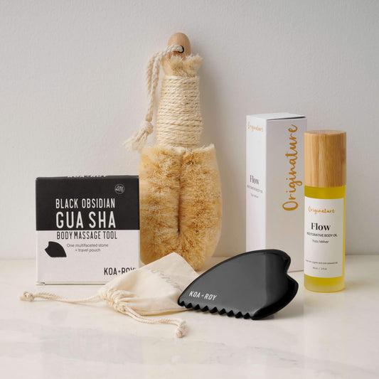 Collection of skincare and wellness products including a gua sha tool, body brush, and oil on a neutral background.