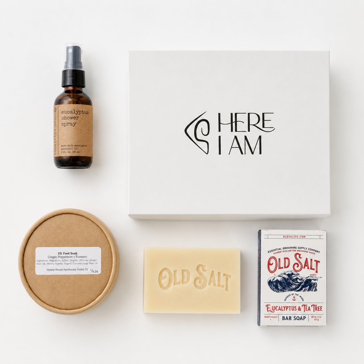Overhead view of skincare and personal care products including eucalyptus room spray, foot soak, soap, and box on a white  gift box.