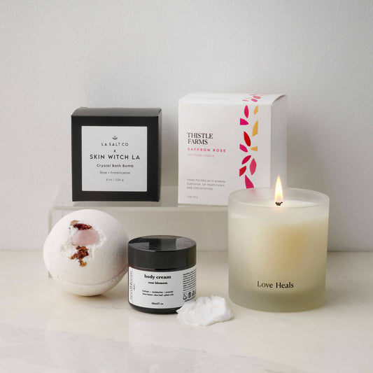 Love Heals candle with rose blossom lotion and a rose crystal bath bomb on a counter