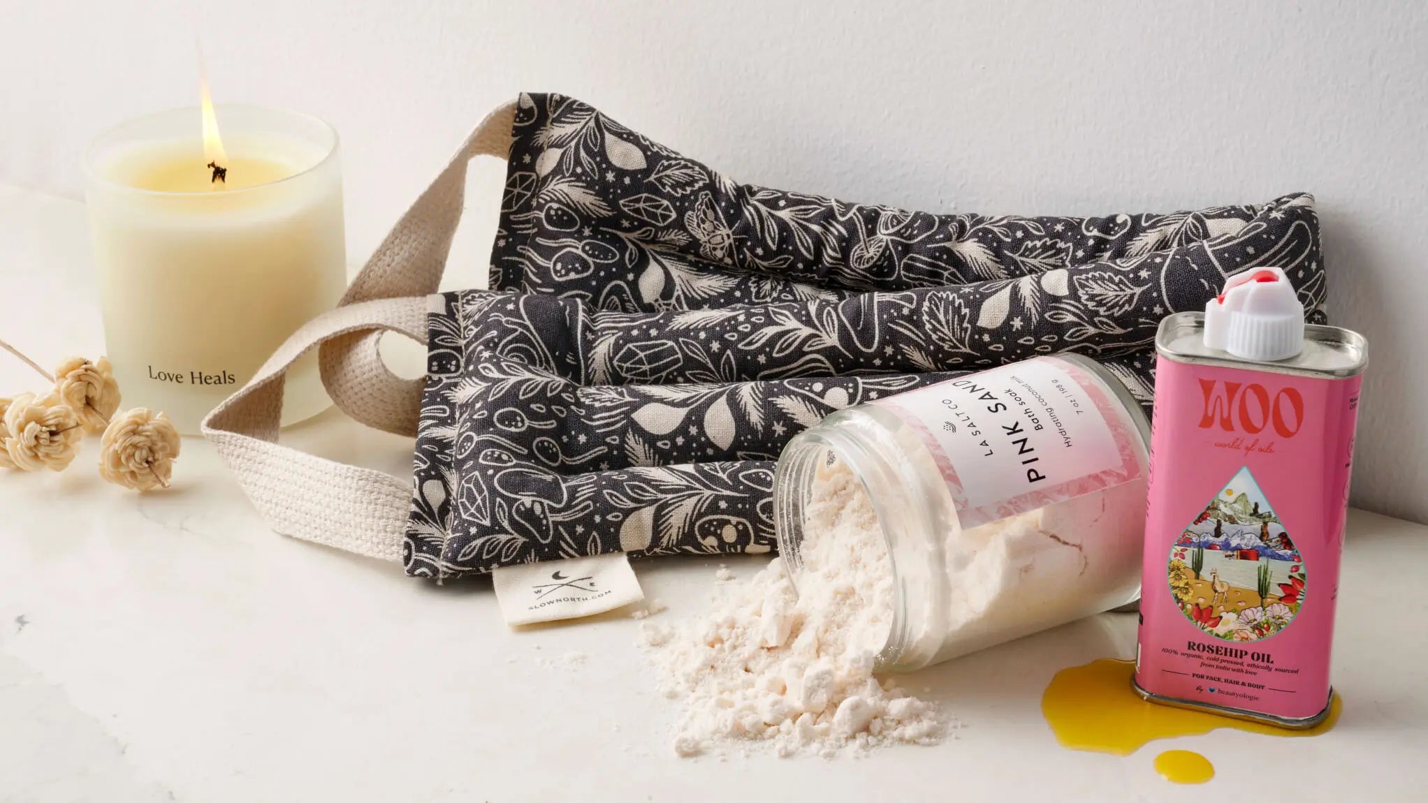 Ethically made self-care products from women-owned brands with bath salts, neck wrap, candle, and skincare oil. 