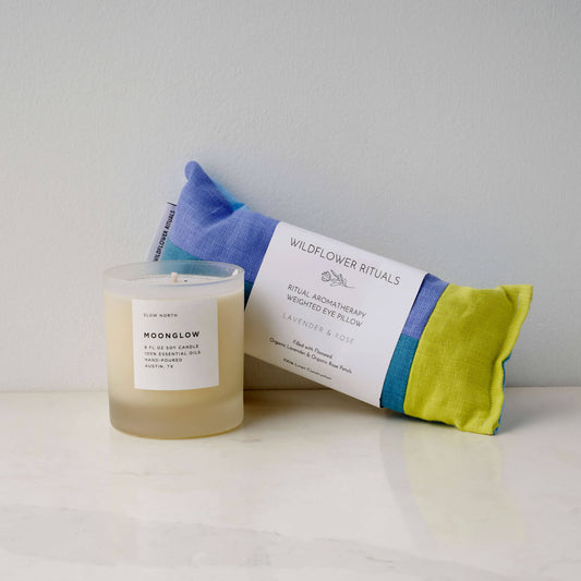 Items for a Pause, including the Moonglow Essential Oil Candle and Lavender & Rose eye pillow, on a counter