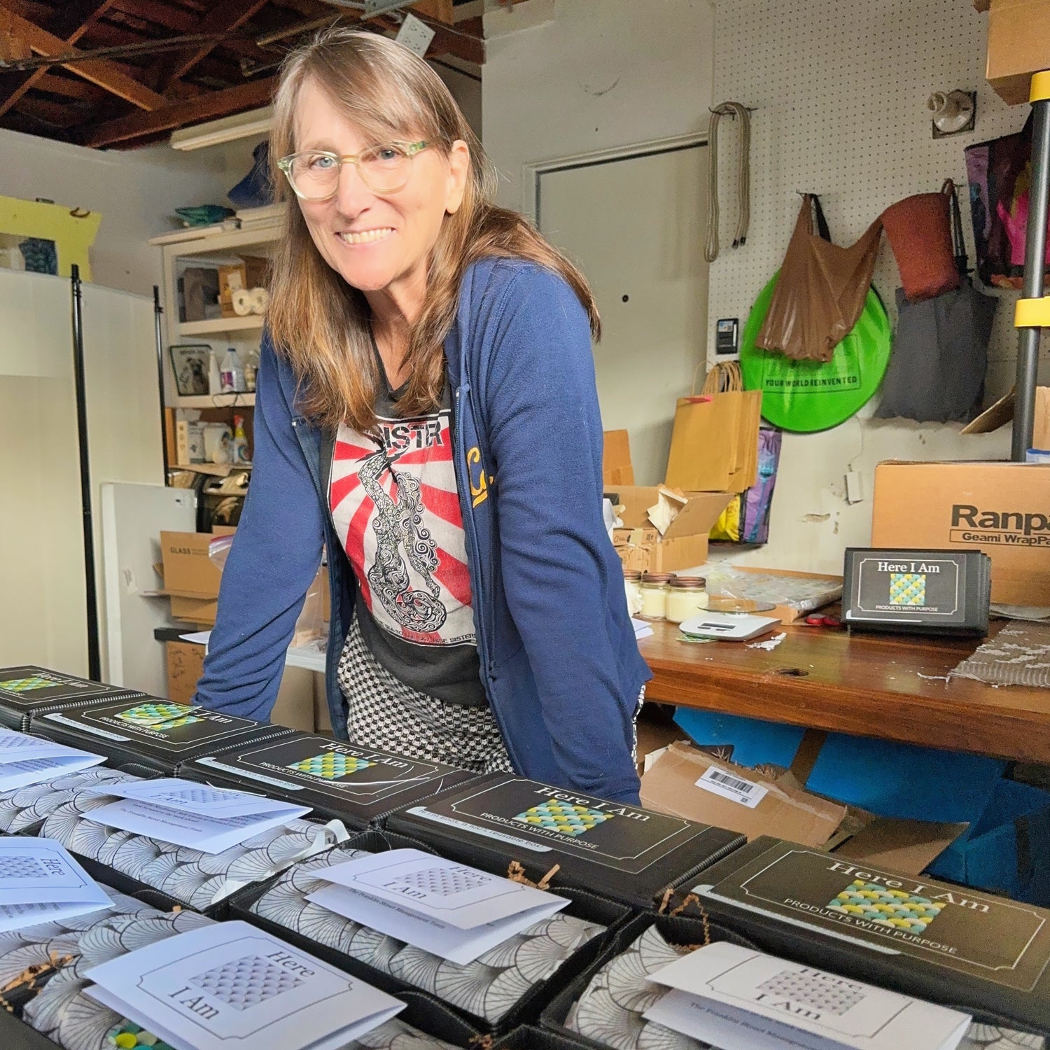 Photograph of Renee in the workshop standing over a table full of boxes ready to be shipped