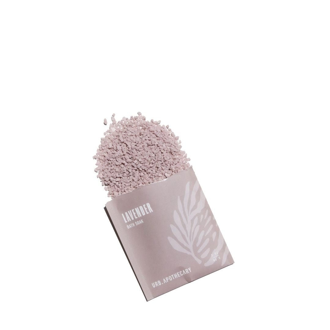 A single pouch of URB Apothecary Lavender Mineral Bath Soak open with lavender granules spilling out on a solid white background.