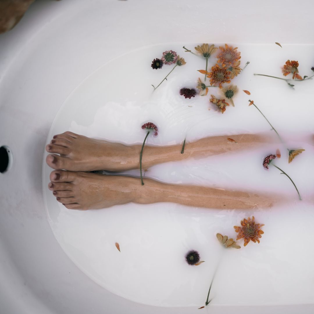 Feet in a bathtub filled with milk and flowers