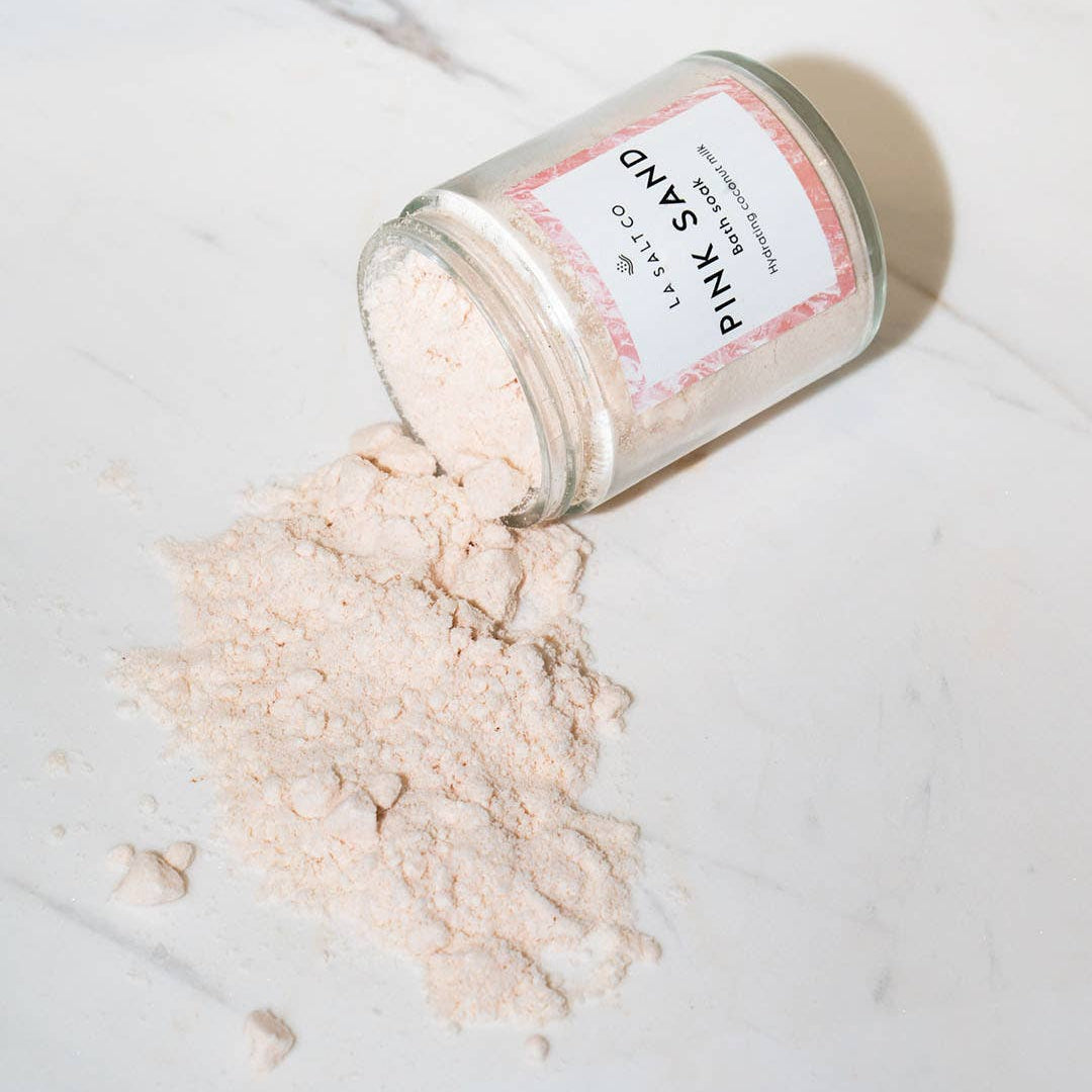Jar of pink sand coconut milk bath soak
with a label on a marble surface