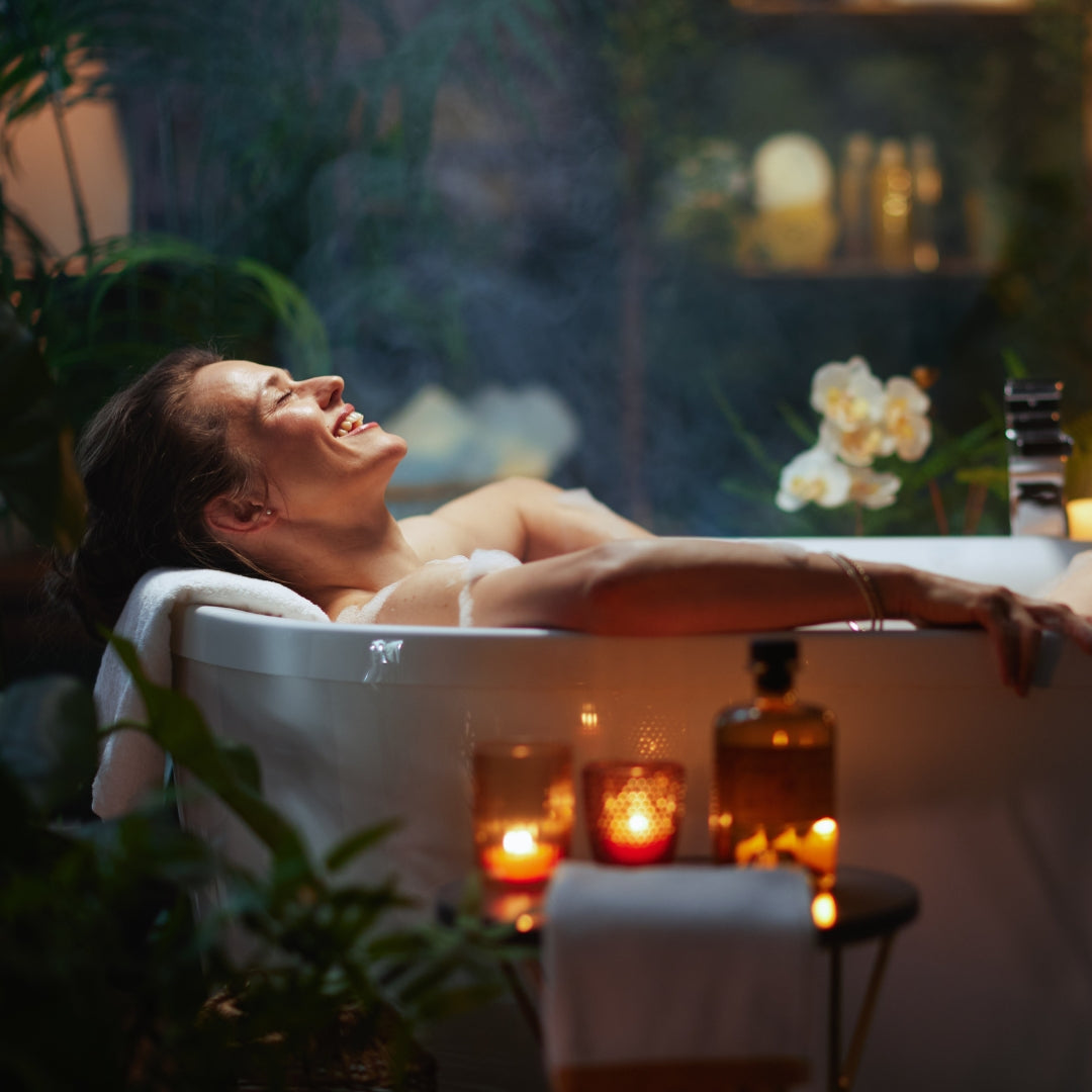 Woman relaxing in a blissful bath with candles and plants around
