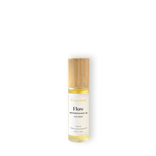 Bottle of 'Flow' restorative body oil with a wooden cap on a light background.
