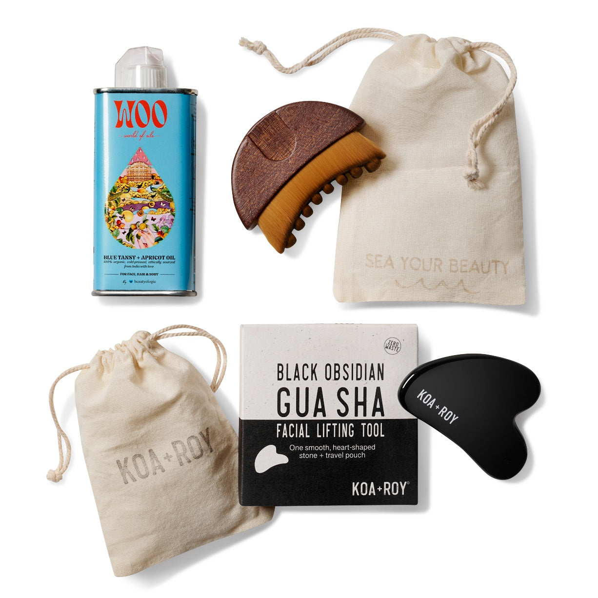 Overhead view of the products in the Flow Facial gift box including a tin of Blue Tansy and Apricot facial oil, a stone gua sha for face with a bag and box, and a gua sha brush with a drawstring bag on a white background