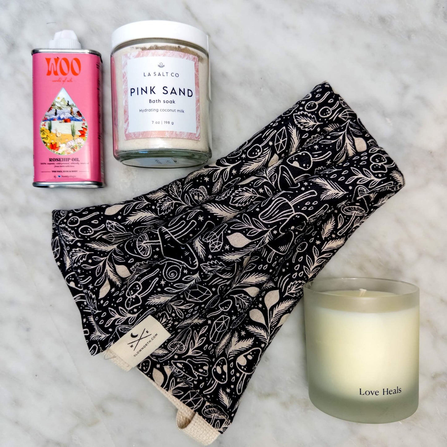 Overhead photo of the contents of the Rest & Relaxation Gift Box including weighted neck wrap, candle, oil, and Pink Sand bath soak