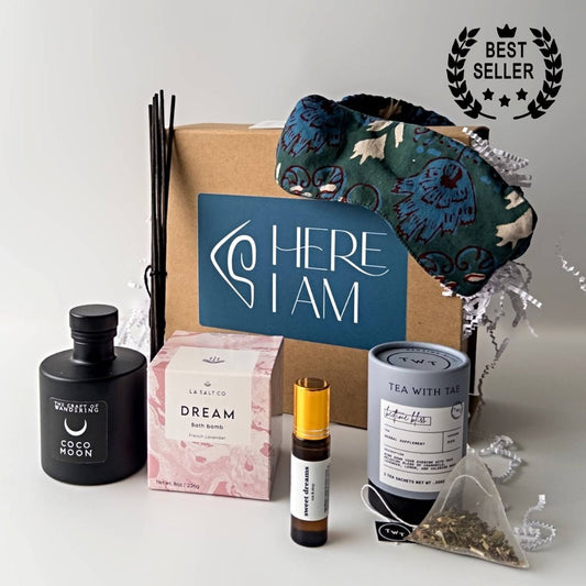 Items from the Sweet Sleep Natural Sleep kit including bath bomb, eye mask, aromatherapy, and tea in front of a wrapped gift box. 