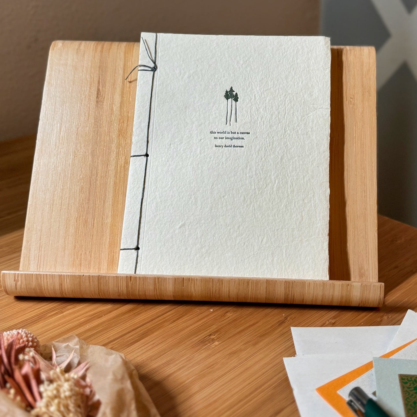 Handmade paper journal with green trees and a quote from Henry David Thoreau printed on cover