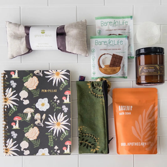 Products in the Empty Nest Gift Box with eye pillow, bath salts, candle, journal, and hot cocoa.
