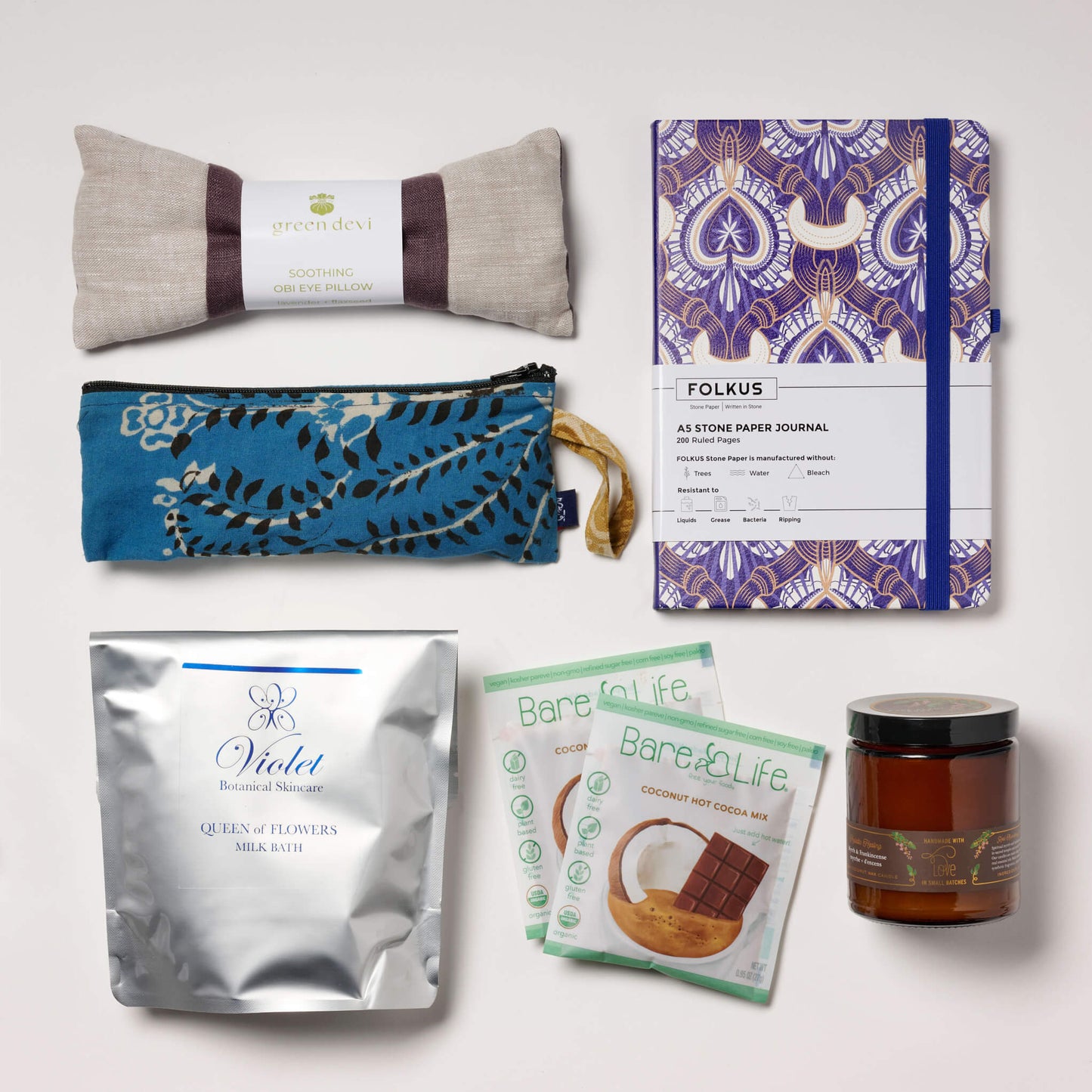 Products in the Wiser Box with eye pillow, bath milk sachets, candle, journal, and hot cocoa.