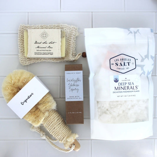 Contents from the Magnesium Scrub Box, including Zechstein sea salts, a natural fiber body brush, eucalyptus shower spray, and dead sea salt soap.