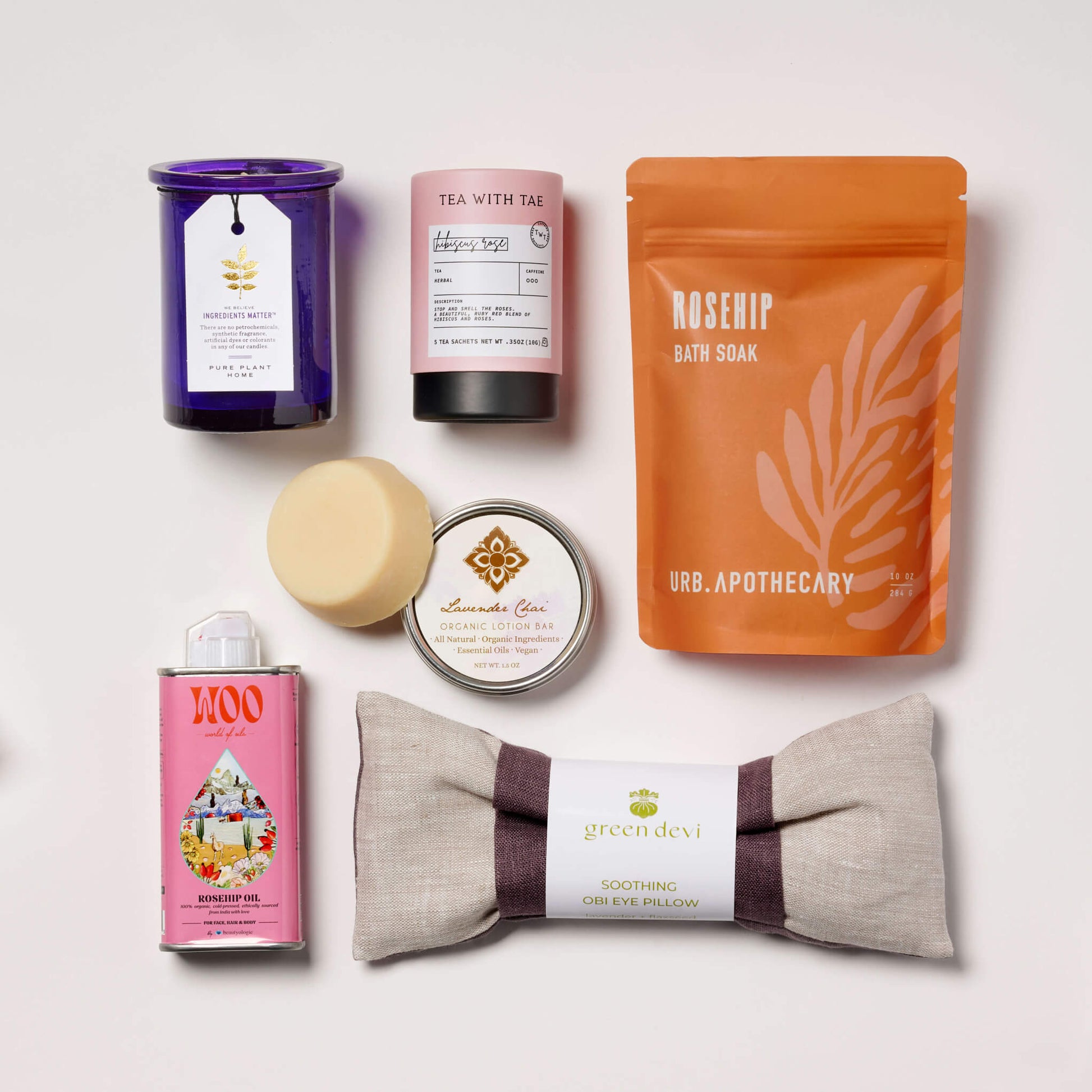 Collection of wellness products with Rosehips and Lavender including a candle, soap, and tea on a textured surface