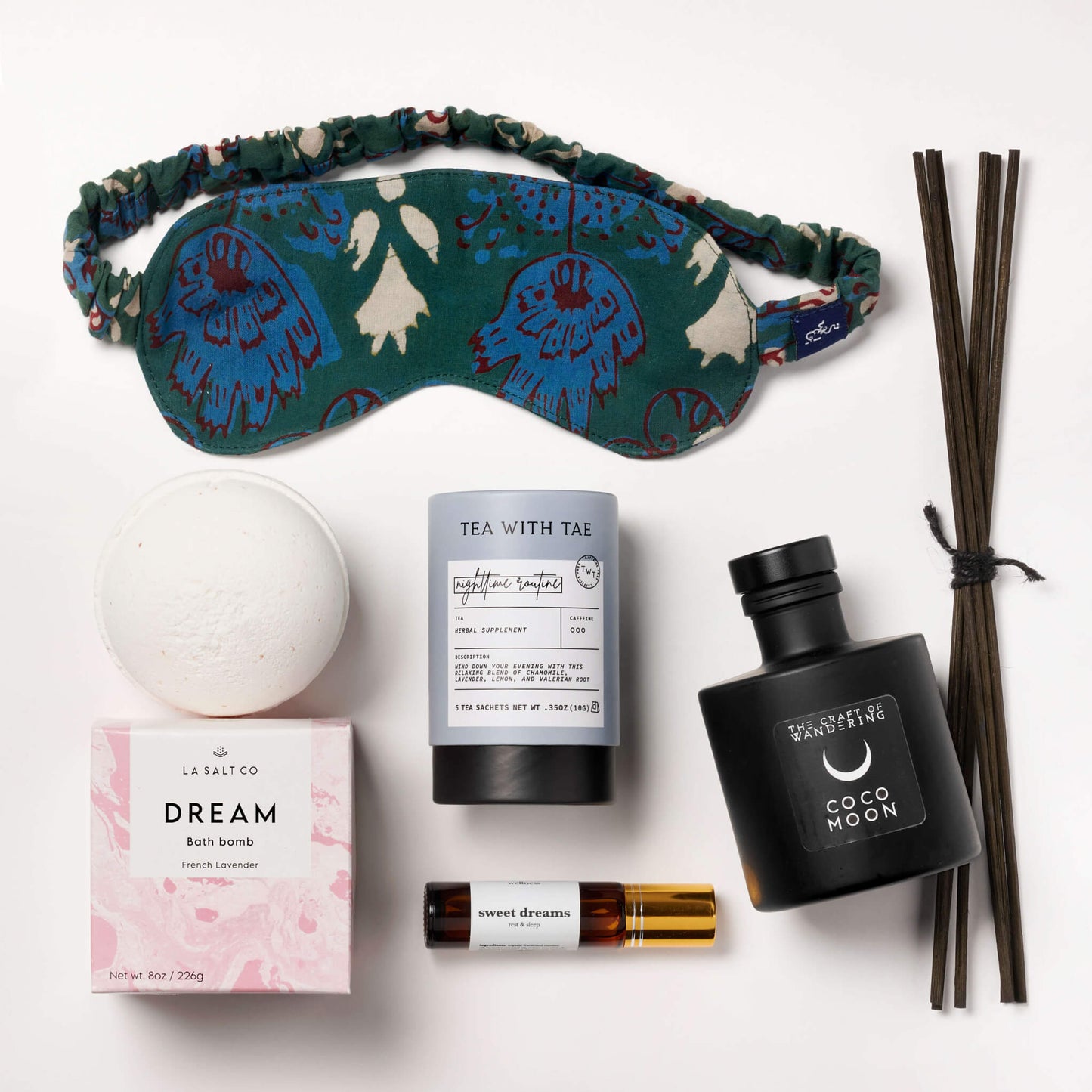 Items from the Natural Sleep kit including bath bomb, eye mask, aromatherapy, and tea on a marble counter.