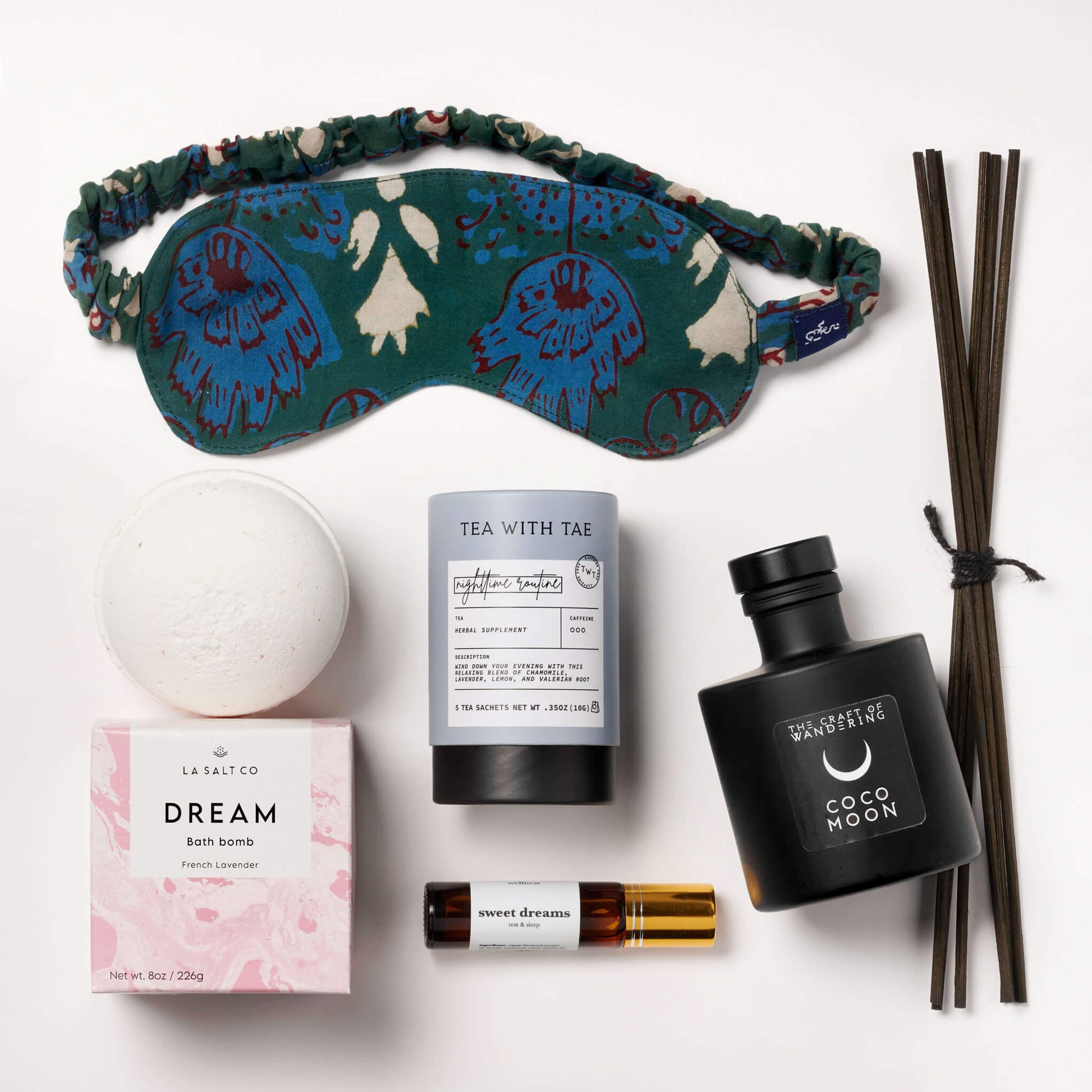 Items from the Natural Sleep kit including bath bomb, eye mask, aromatherapy, and tea on a marble counter.