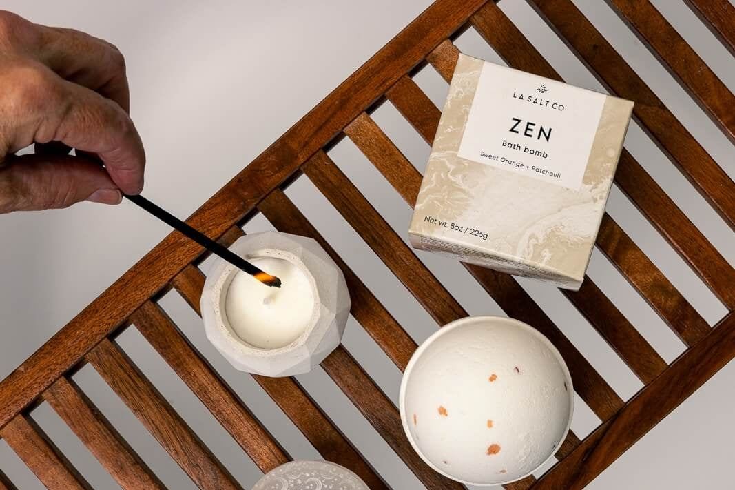 A minimalist self-care routine with bath bomb and candle over bath