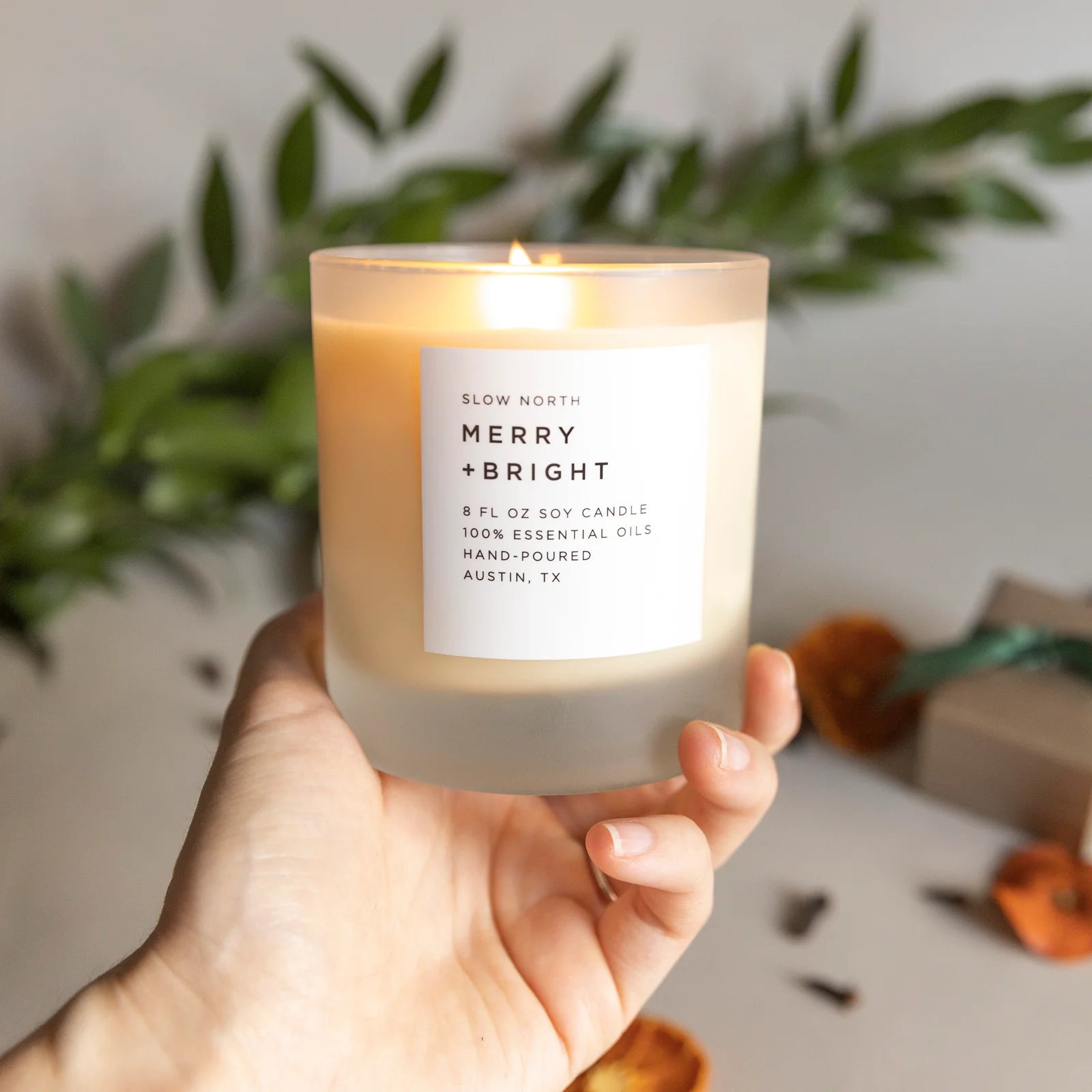 Merry and Bright essential oil candle from Slow North with greenery