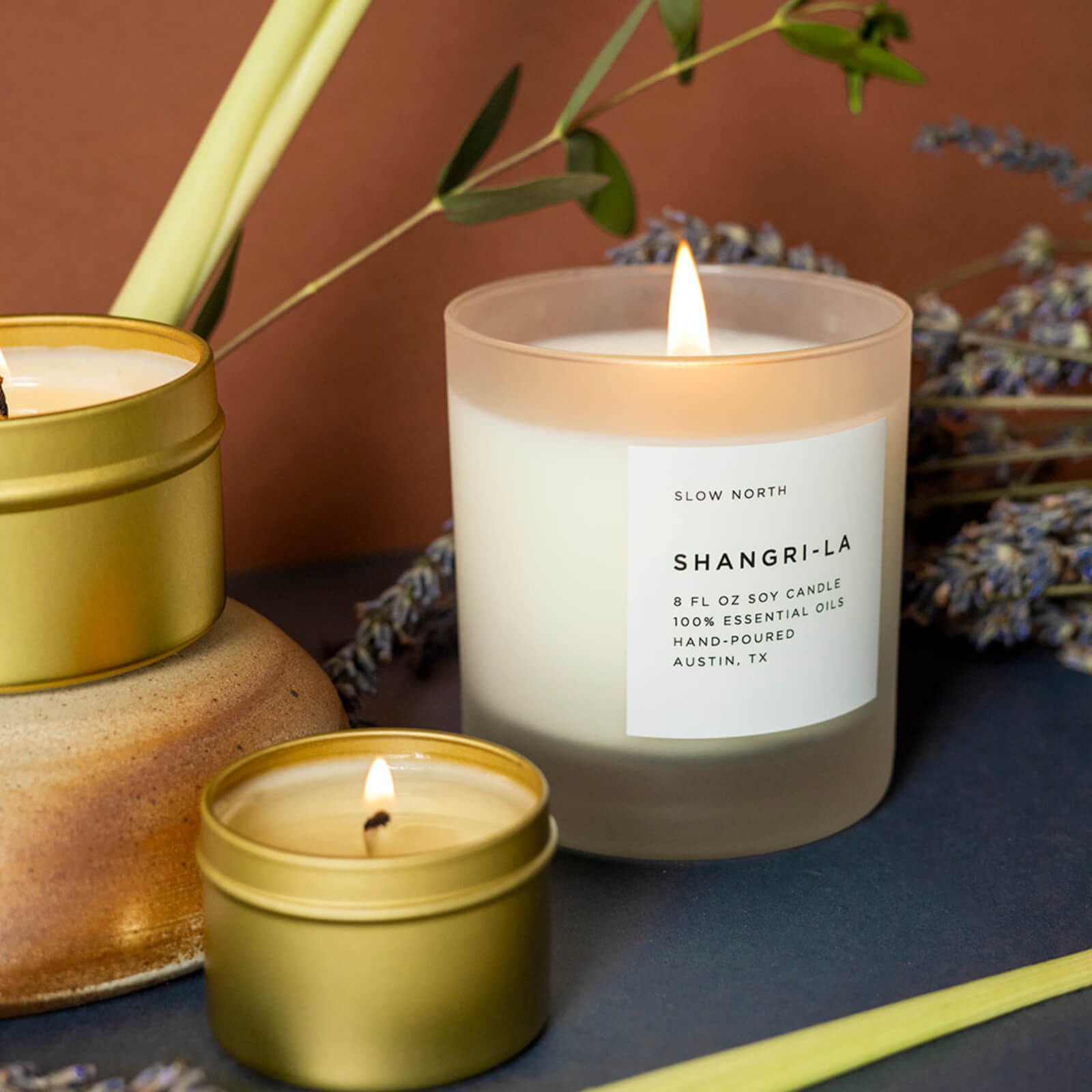 The Shangri-La scented candle on a shelf with dried lavender and other candles