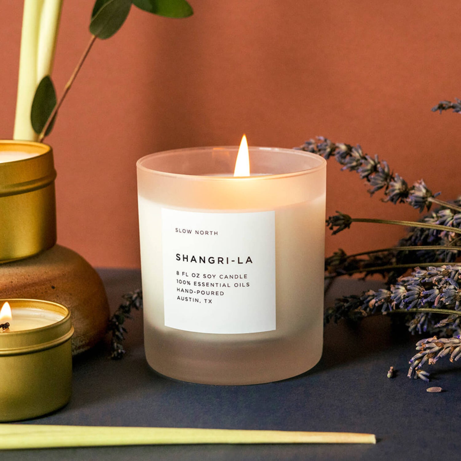 The Shangri-La candle on a shelf with lavender and lemongrass cuttings