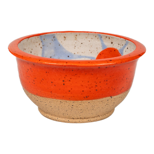 A small ceramic bowl with orange rim and blue daisies on the inside