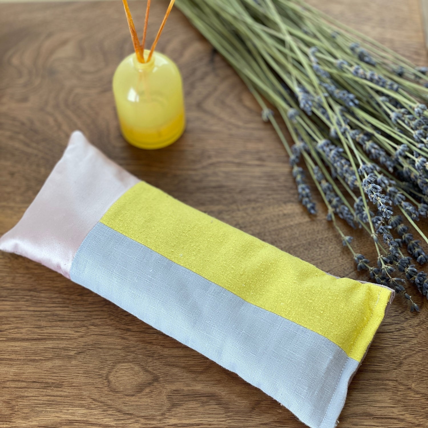 The lavender and rose eye pillow on a table with fresh lavender fronds