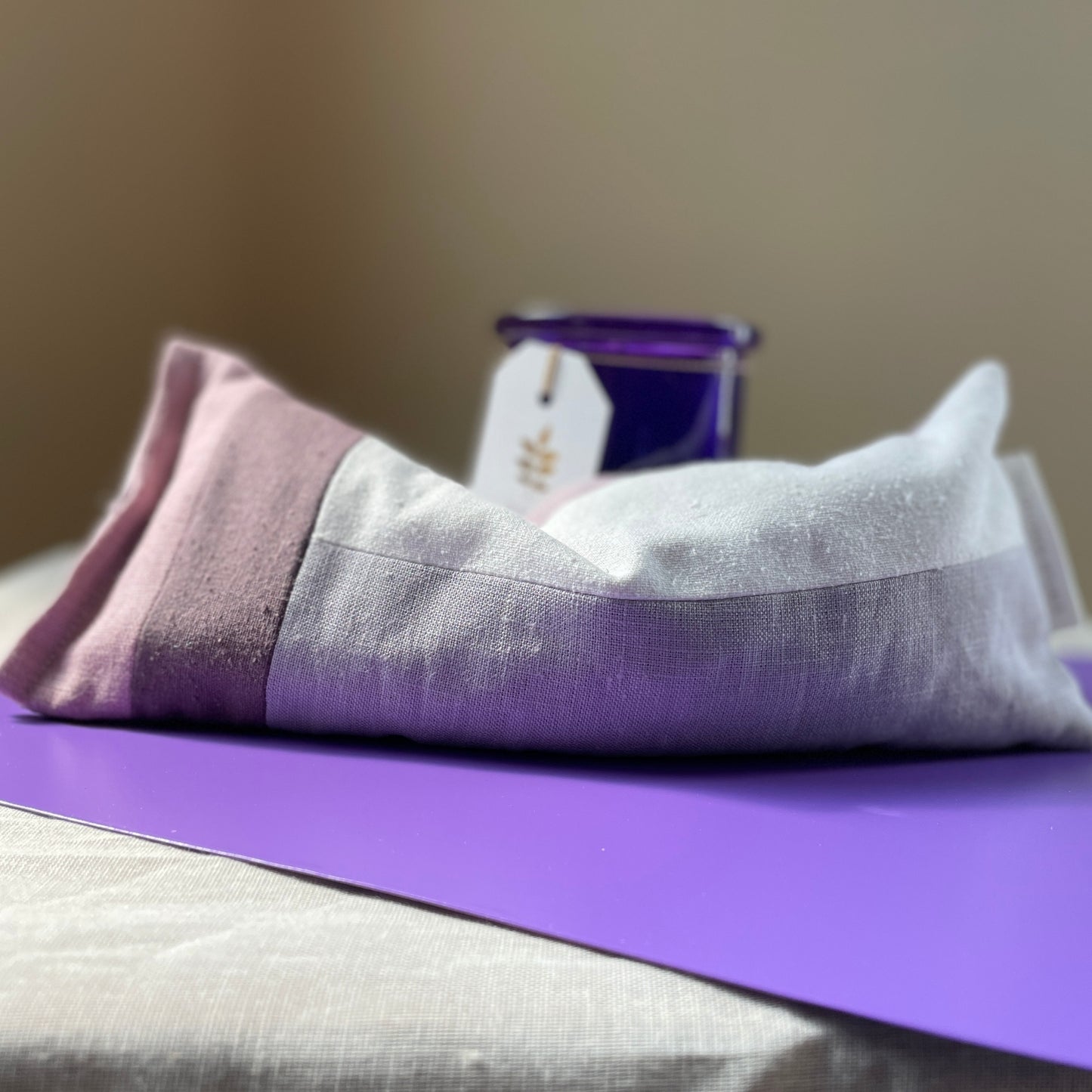Aromatherapy Weighted Eye Pillow on purple card with candle in background